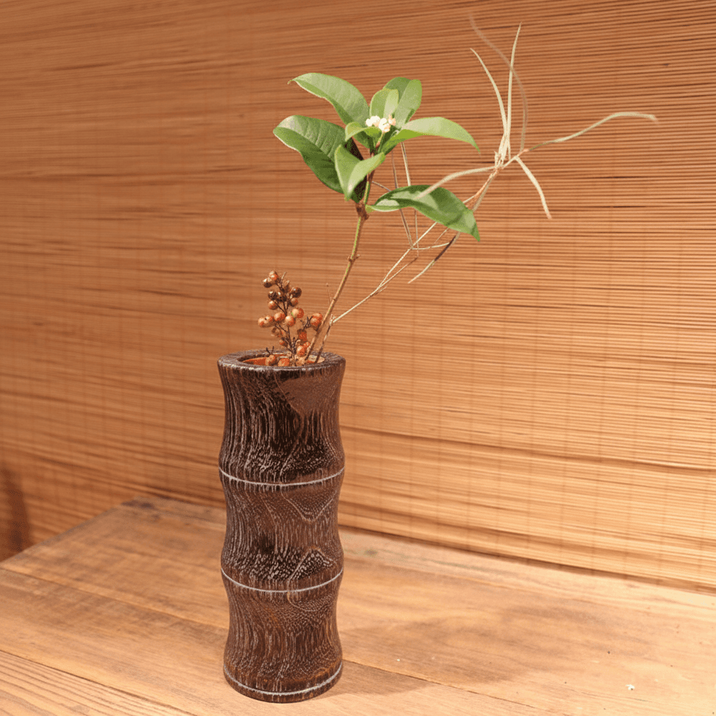 Rin Essense wood vase with carved texture holding decorative green leaves and twigs on wooden surface
