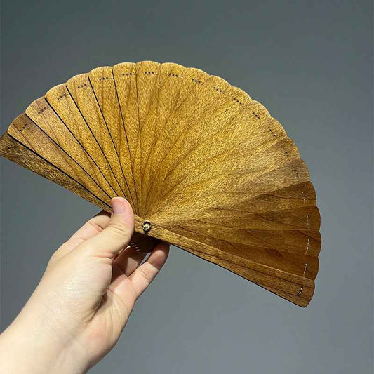 Hand holding a wooden folding fan hand by Rin Essense with a natural wood finish