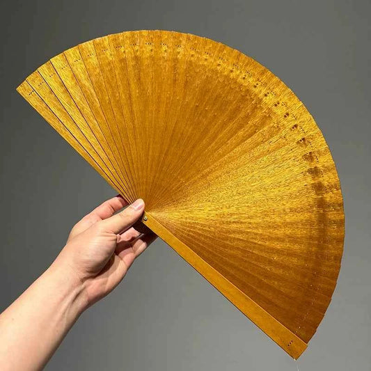 Rin Essense golden folding fan hand held open against gray background