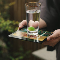 Yamanaka Lacquerware Makie Coaster – Timeless Japanese Craft holding clear glass of water with green fruit