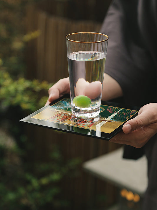 Yamanaka Lacquerware Makie Coaster – Timeless Japanese Craft holding clear glass of water with green fruit