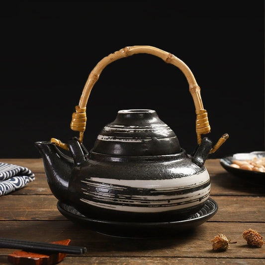 Kokoro ceramic tea set black striped teapot with bamboo handle on matching saucer on wooden table